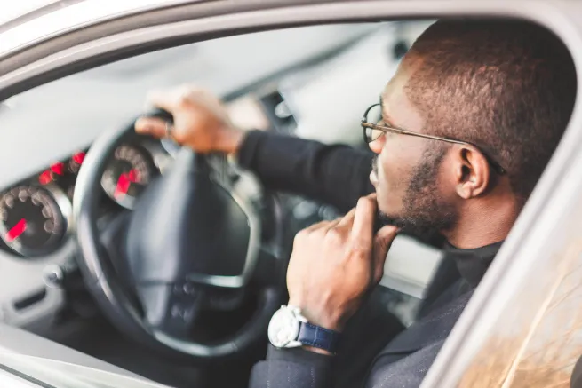 Mann mit Brille am Auto eines Steuers
